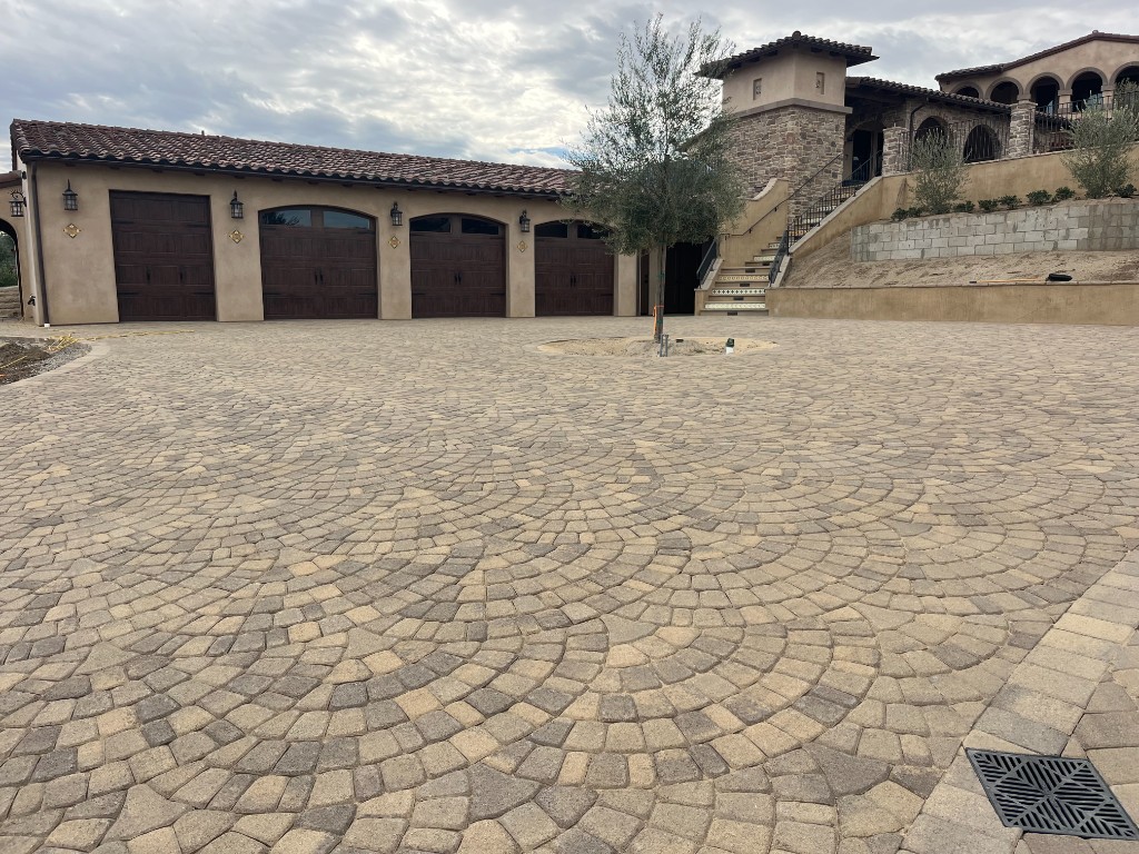 Custom paver driveway with decorative pattern leading to garage and entry