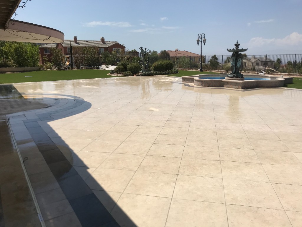 Large paver patio with decorative border, fountain, and lawn