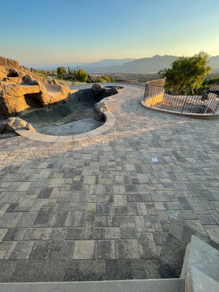 Paver pool deck with rock feature, coping, and patio